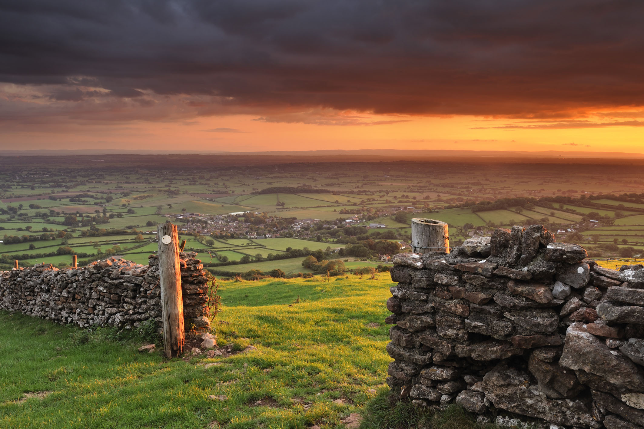 A fiery sunset breaks underneath storm clouds at Cook's Fields on the Mendip hills, Somerset.